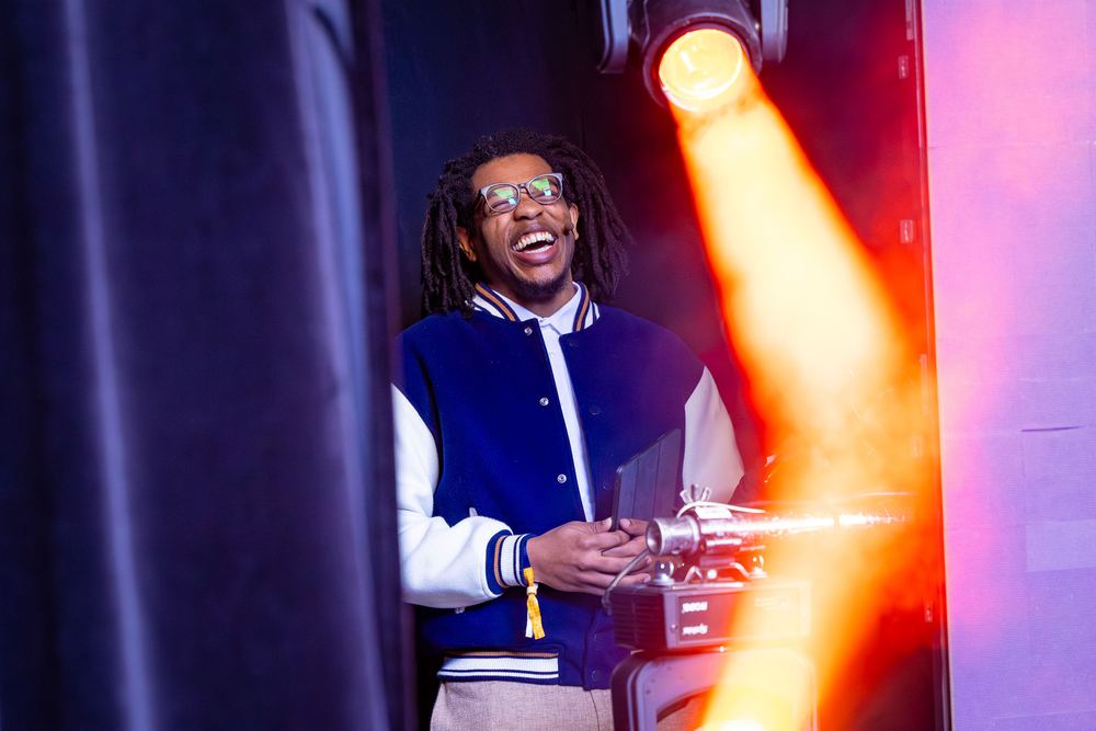 Terrance laughing backstage at DPW New York under an orange spotlight