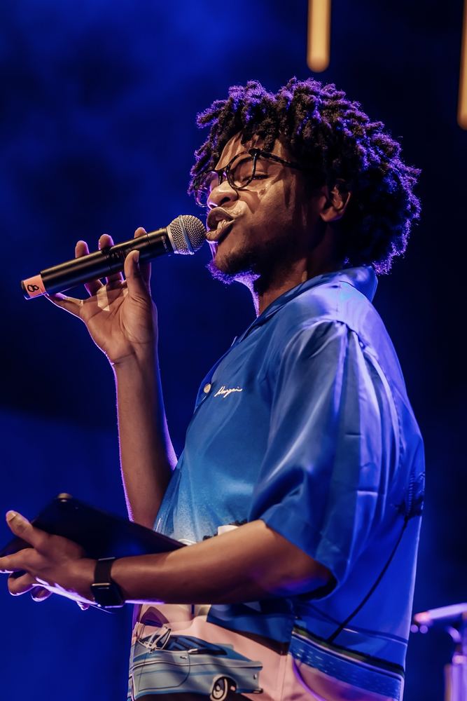 Terrance speaking into a handheld microphone on a blue-lit stage